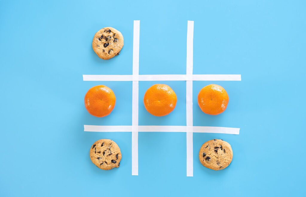 Tres en raya de cookies y mandarinas sobre un fondo azul