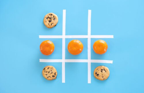 Tres en raya de cookies y mandarinas sobre un fondo azul