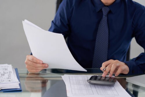 Persona sentada en escritorio realizando contabilidad y facturas